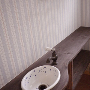 トイレ：リビングシェルフと同じ無垢材のカウンターに、洗面ボウルの落ち着いた柄が映えます