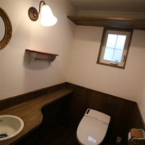 トイレ：ダークトーンの腰壁とウッディなカウンター。小洗面のカランや鏡など、アンティークなテイストでまとめました。