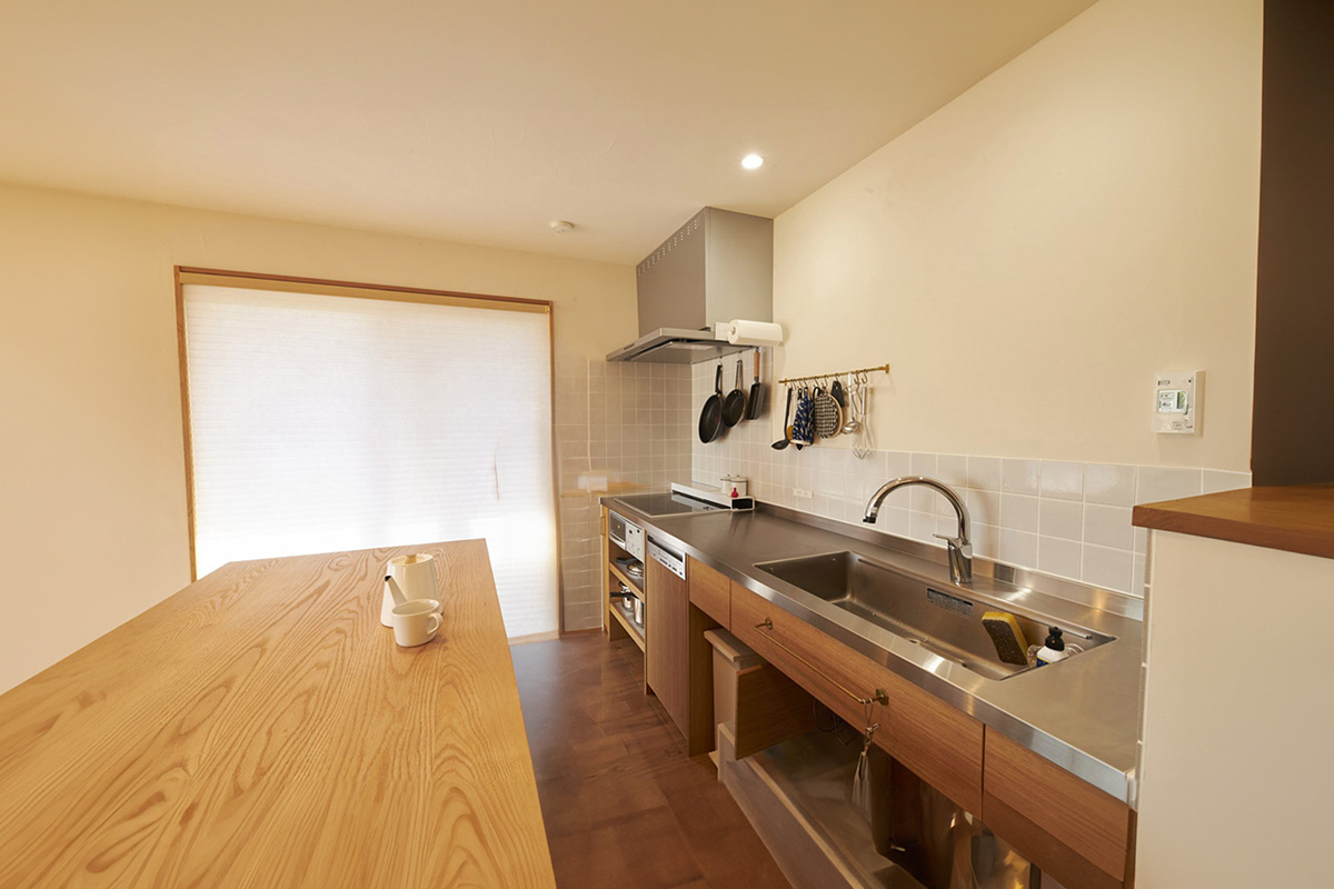 壁のタイルと真鍮が良くはえるシンプルで機能的なオーダーキッチン