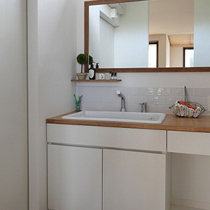 実験用シンクに造作カウンターを合わせたオリジナルの洗面台。白のタイルを使用し、明るく清潔感のある洗面室に。