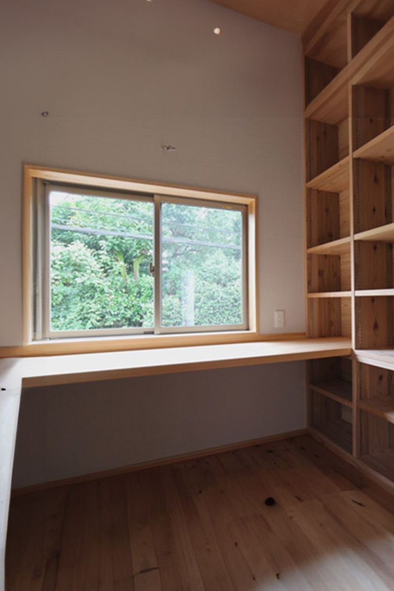 ２階の書斎。右が本棚。正面に作り付けのデスクと樹木を望む窓。
