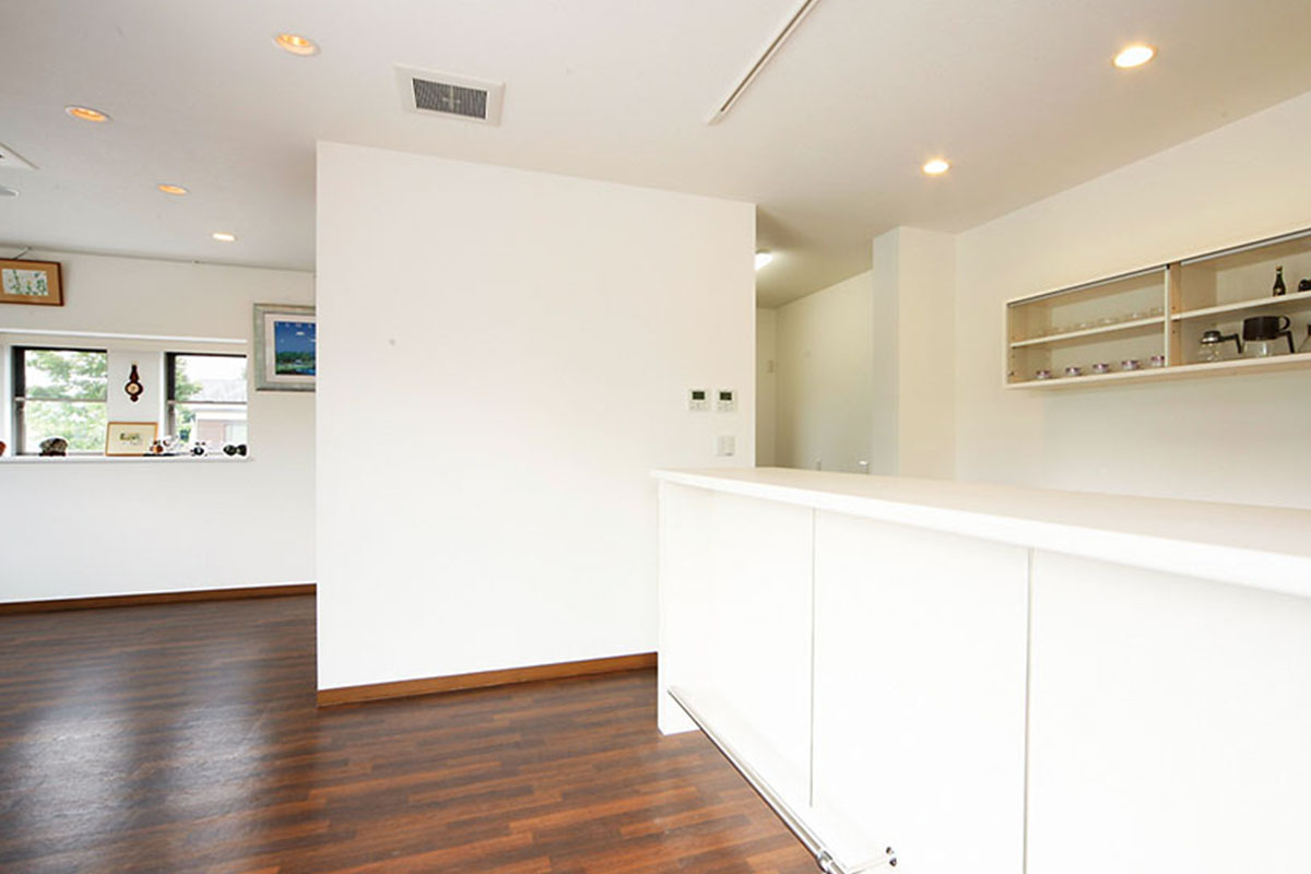 白い壁とダークブラウンの床のコントラストが引き立つ1階のカフェ。本格的な厨房も設置