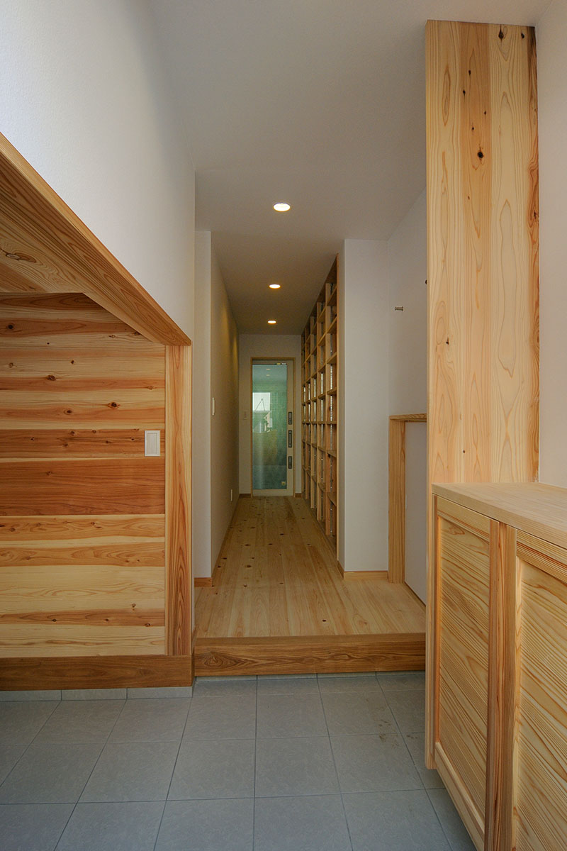 玄関、左に杉無垢板はりの収納、廊下には本棚
