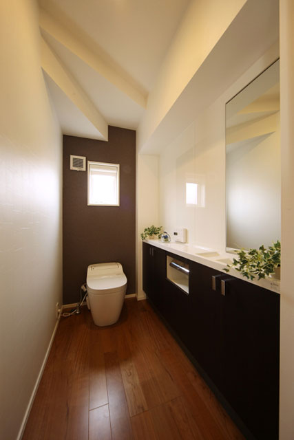 壁一面の収納があるトイレはパネルを張り清潔感を強調しました。