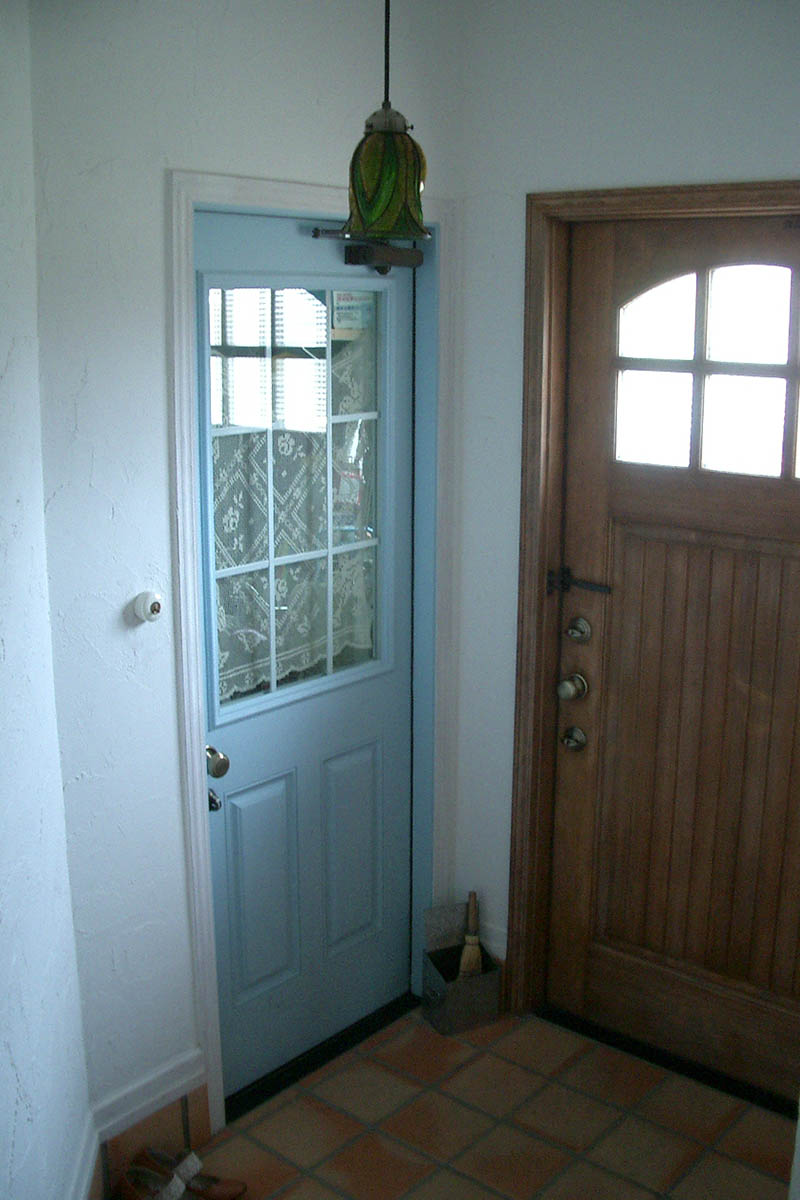 玄関：あたたかな質感の木製ドアに、こだわりのテラコッタタイルを合わせた上質なエントランスホール