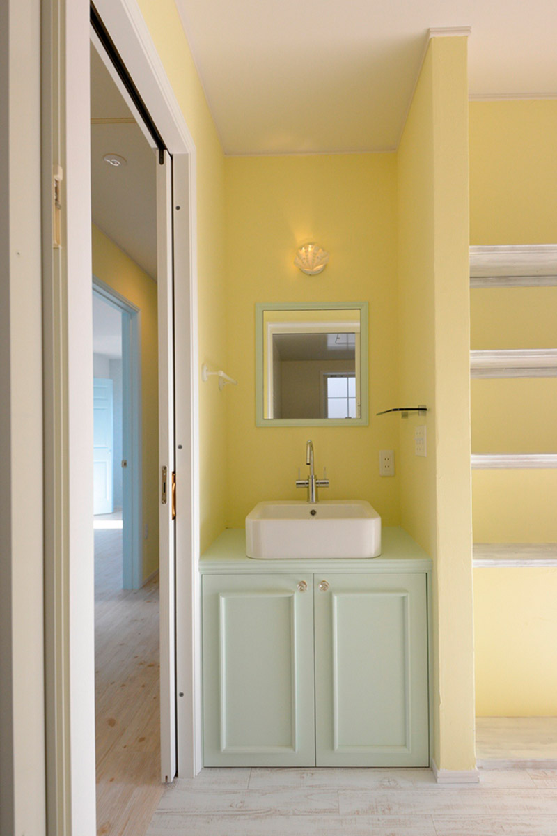 洗面：柔らかな色使いの洗面。収納と鏡を淡くやわらかなカラーで統一。
