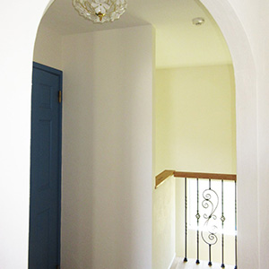 廊下：アーチから覗く階段・アイアン・ペイントドアにかわいい照明。1つの物語のような空間です。