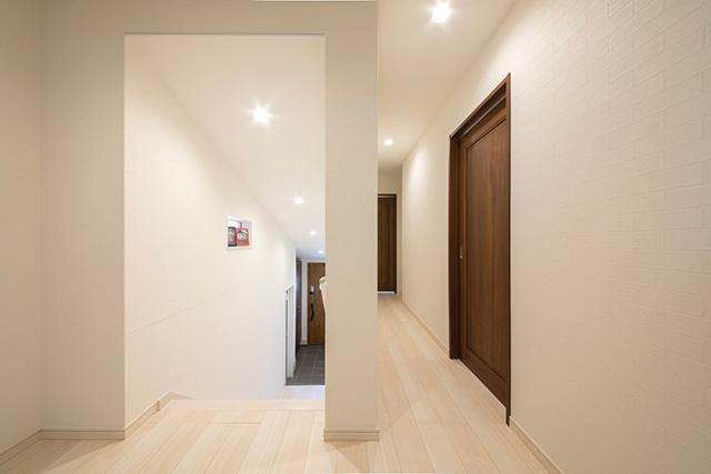 廊下：敷地の高低差を活かし、中二階のようなステップフロア設計。各部屋への日当たりやプライベート空間の自然な分離にもなる配置です。