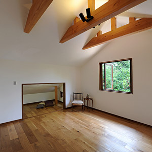 2階の一部屋。天井の梁が特徴的。屋根の勾配もあるため奥には、収納スペースとしても利用できる空間を設けた。