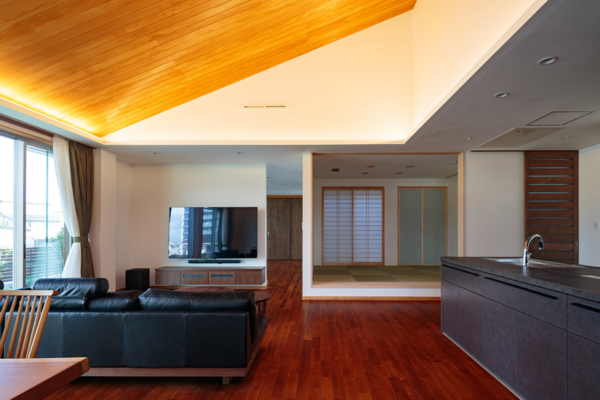 LDKから小上がりの和室。勾配天井には、床とは異なる色味の木材と間接照明を設けることでより開放的に。