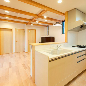 １階親世代のリビングダイニングキッチンは、天井に構造体の無垢の梁を見せるデザイン。キッチンはタイル貼りでお掃除も簡単。