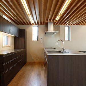 大工さん工事で作り付けにした対面式のキッチンと食器棚です。シンクは天板のステンレスと一体成形になっています。
