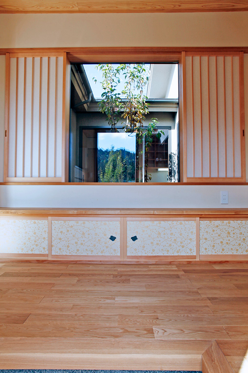 玄関：玄関ホールです。玄関に入ると中庭が見えて明るい玄関になっています。地袋収納の襖戸は京都のからかみの老舗・唐長さんから取り寄せたからかみを使って建具屋さんに制作してもらっています。