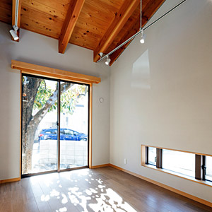 玄関とつながる土間ギャラリーです。梁を現しにして屋根なりの勾配天井にして開放的な空間になっています。