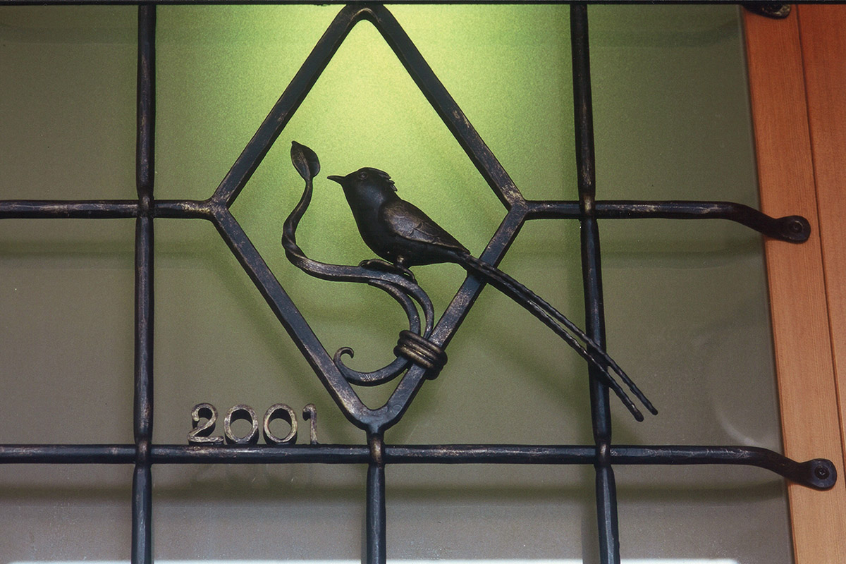 玄関扉のガラスのところには鍛鉄工芸家に特注した鍛鉄の面格子がついています。ほろほろ鳥がとまっています。