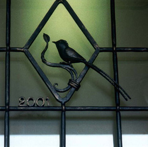 玄関扉のガラスのところには鍛鉄工芸家に特注した鍛鉄の面格子がついています。ほろほろ鳥がとまっています。
