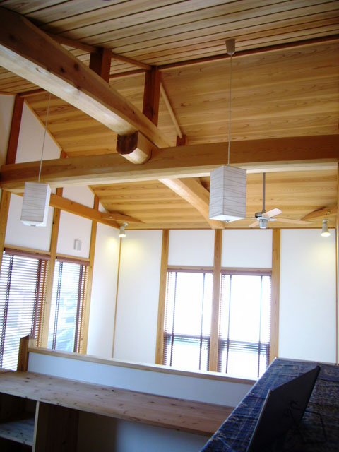 吹き抜けの上部とそれに隣接する共用スペース。杉のタイコ梁を十字に架け、天井は杉板を屋根勾配なりに施工、セルロースファイバーによる断熱。