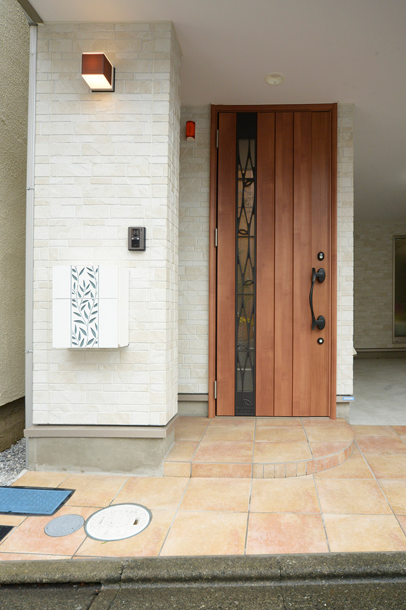 明るい外壁に重厚な印象の玄関ドア。アイアンワークが軽やかさを演出。