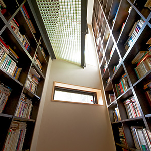 地下から1階を見上げる書棚、棚板を少し傾け落ちにくい