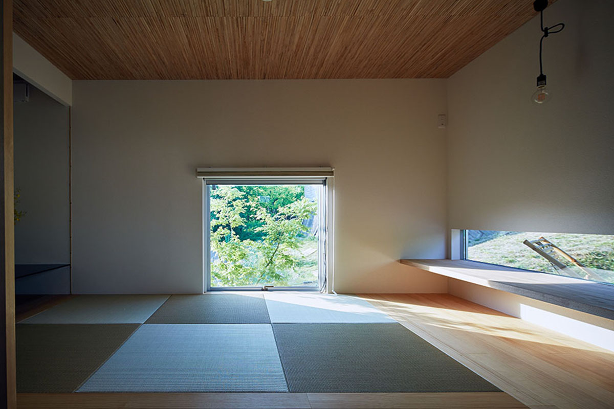 縁なしの畳にガマシン張りの天井、緑の借景をスクエアに切り取る地窓が印象的な趣のある和室