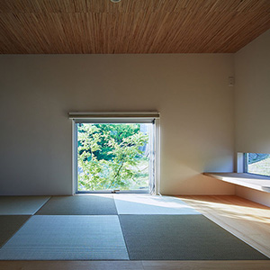縁なしの畳にガマシン張りの天井、緑の借景をスクエアに切り取る地窓が印象的な趣のある和室
