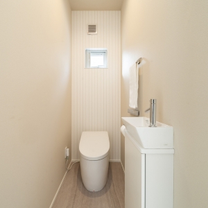 角型手洗いカウンターと採光窓を備えた、清潔感あるトイレ空間