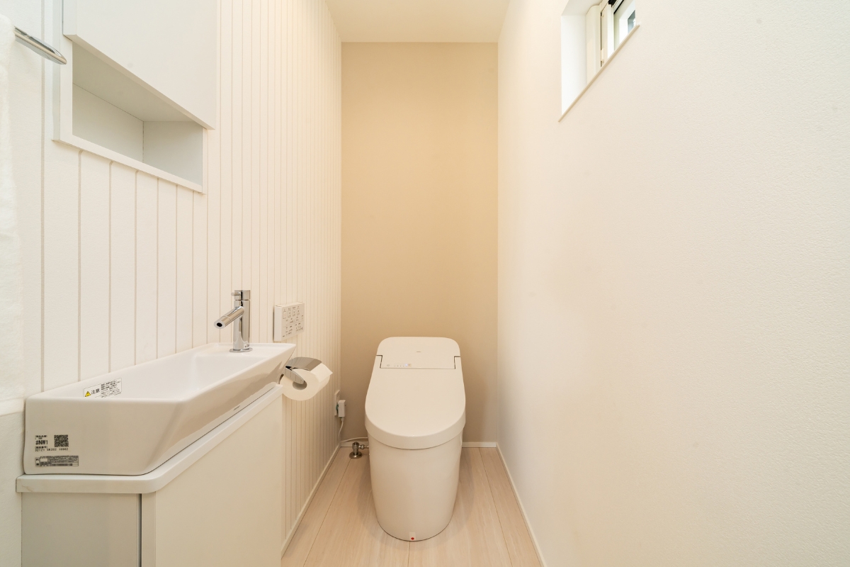 タンクレス風トイレと横長手洗いカウンターを備えた、すっきり縦長のトイレ空間