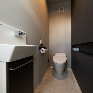 壁掛け手洗い器とダークカラー壁面を組み合わせた、上質な陰影のトイレ空間 壁掛け手洗い器とダークカラー壁面を組み合わせた、上質な陰影のトイレ空間