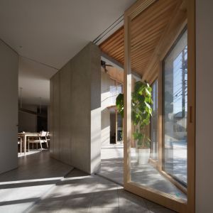 玄関土間。木製建具の先にソラリウムが見え、奥へ視線が抜ける 玄関土間。木製建具の先にソラリウムが見え、奥へ視線が抜ける