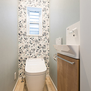 トイレは、壁の一面に植物柄のアクセントクロスを使用しオシャレな空間に。