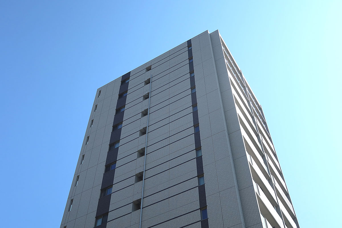 【建築物日照】下から見上げた高層マンションと快晴の空