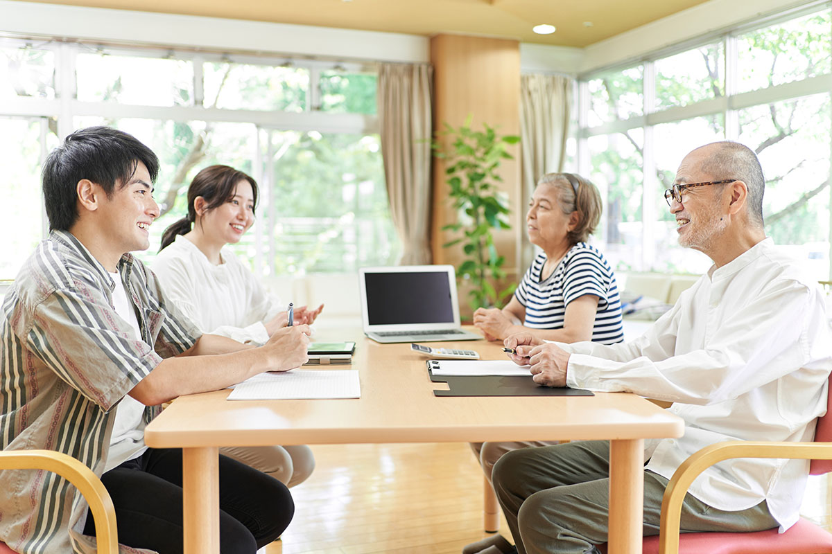 笑顔で会話する若夫婦と老夫婦