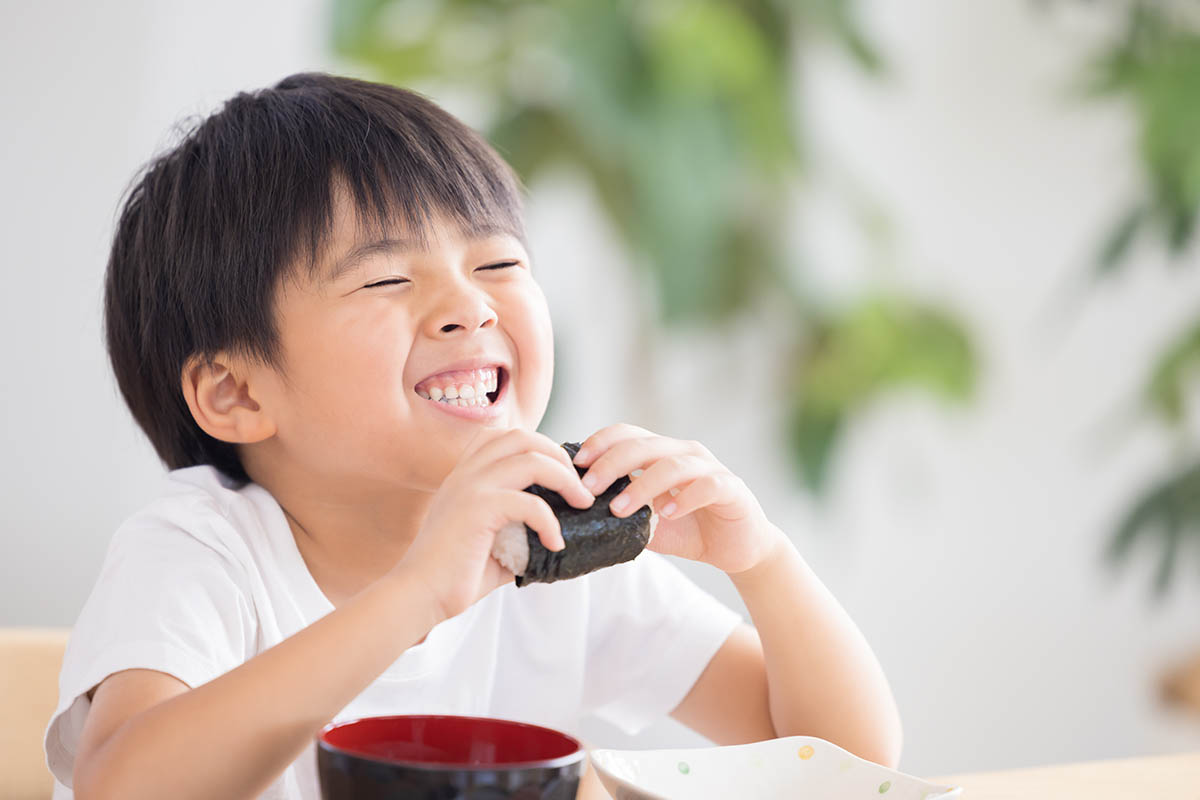ファミリー食事おにぎりを食べている男の子