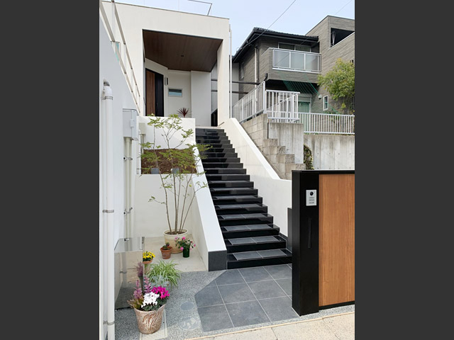 外構：天然石のタイルをふんだんに使ったアプローチの階段は引き締め色のブラック。お家全体を象徴する、シックモダンでおしゃれなエントランスです。