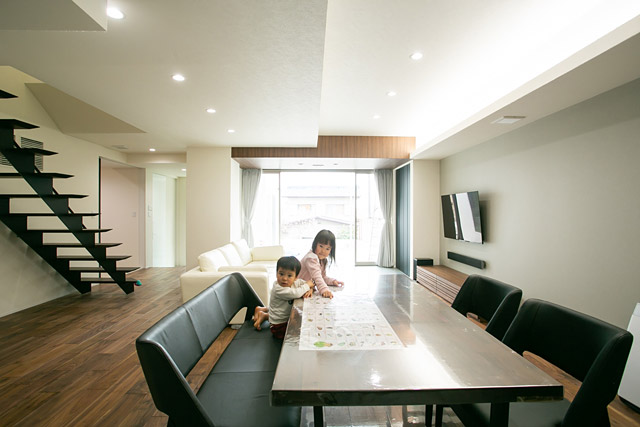 リビング：階段は黒でも重い印象にならないスケルトン階段。濃色調の床・壁の白、日差しのコントラストが絶妙です。全館空調でエアコン室内機が不要で壁面もスッキリ。