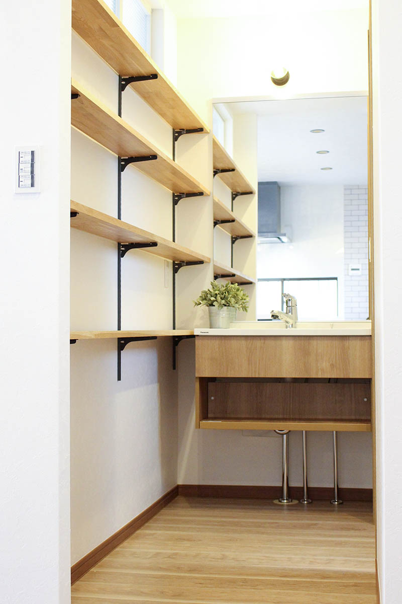 造作の洗面台も壁のオープンラックもオーク材で全体のインテリアとの統一感も◎。