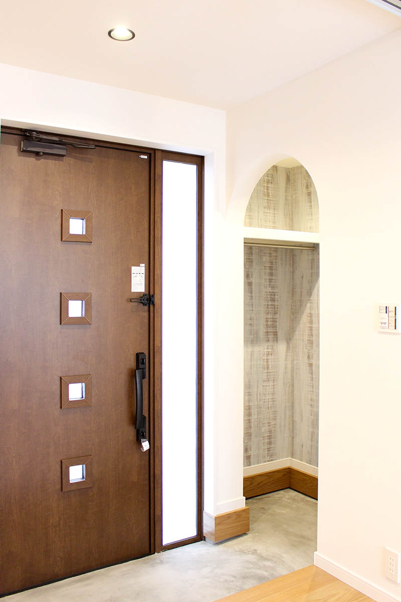 玄関after：アーチ開口とアクセントクロスが印象的な明るい玄関に。土間スペースを拡張して上着もかけられます。