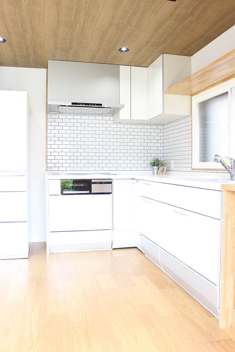 キッチンafter：窓から光が差し込む明るいキッチンになりました。白いキッチン&タイルに木目がよく映えます。