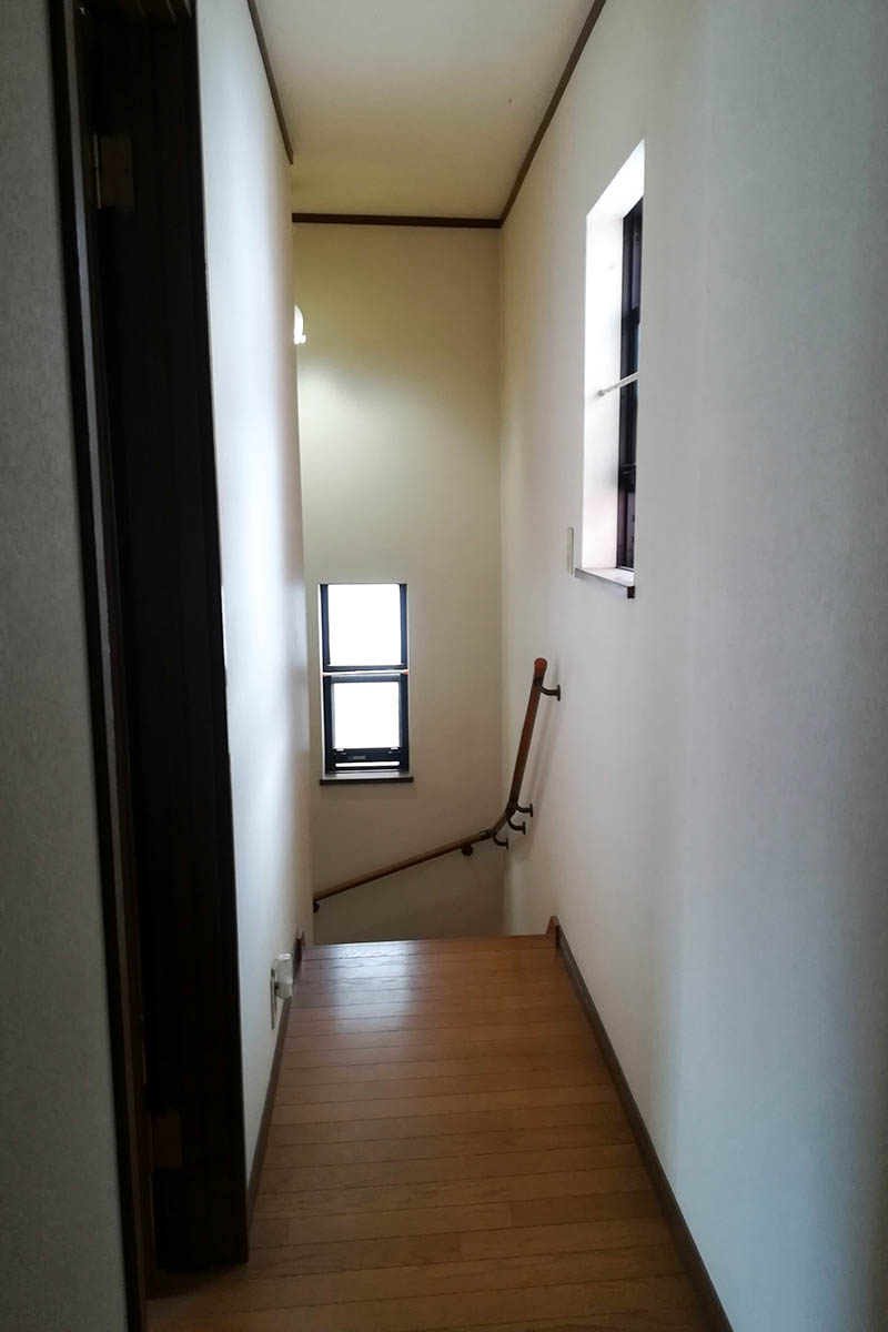 2階廊下before：施工前は照明が少なく、電気をつけても暗い廊下。建具の色も濃い目で暗く狭い印象に。