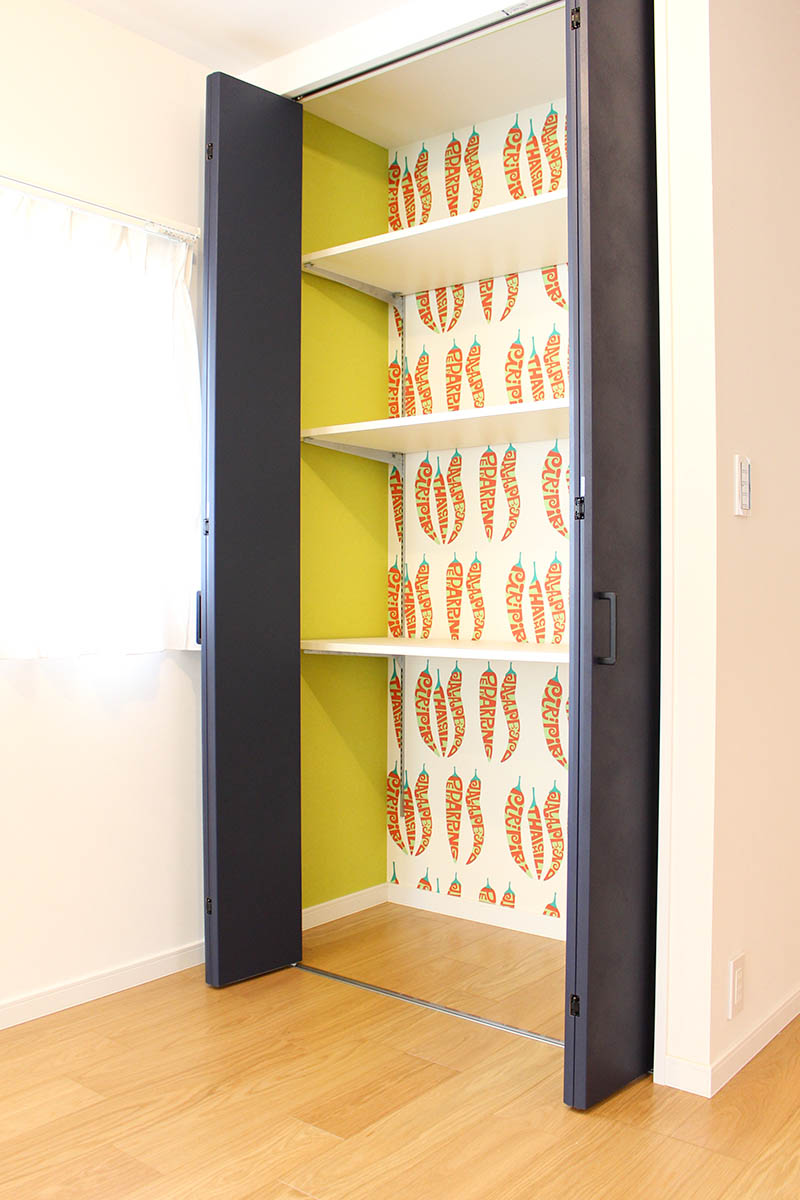 クローゼットの扉を開けると、唐辛子模様のアクセントクロスが！見えない場所に遊び心を取り入れました。