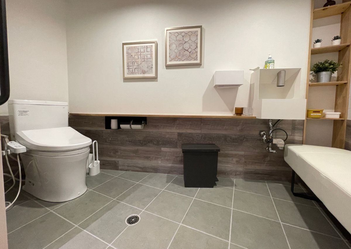 幅広引き戸で広いバリアフリートイレ。オストメイト対応便座やベンチがあり、おむつ替えも可能。