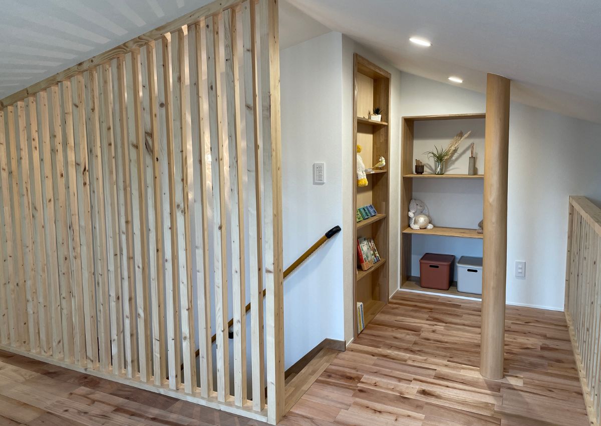 無垢床と木製格子が温かい空間。階段横の棚は実は隠し扉！開け方はヒミツの遊び心あふれる仕掛けです。