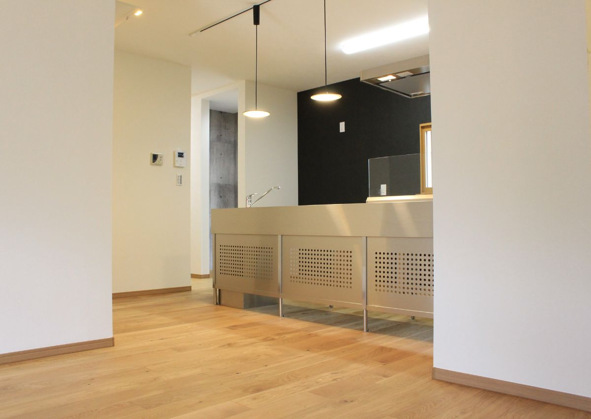 自然素材にこだわり、オークの無垢床を使用。黒い壁紙や照明でステンレスキッチンが映える空間に。