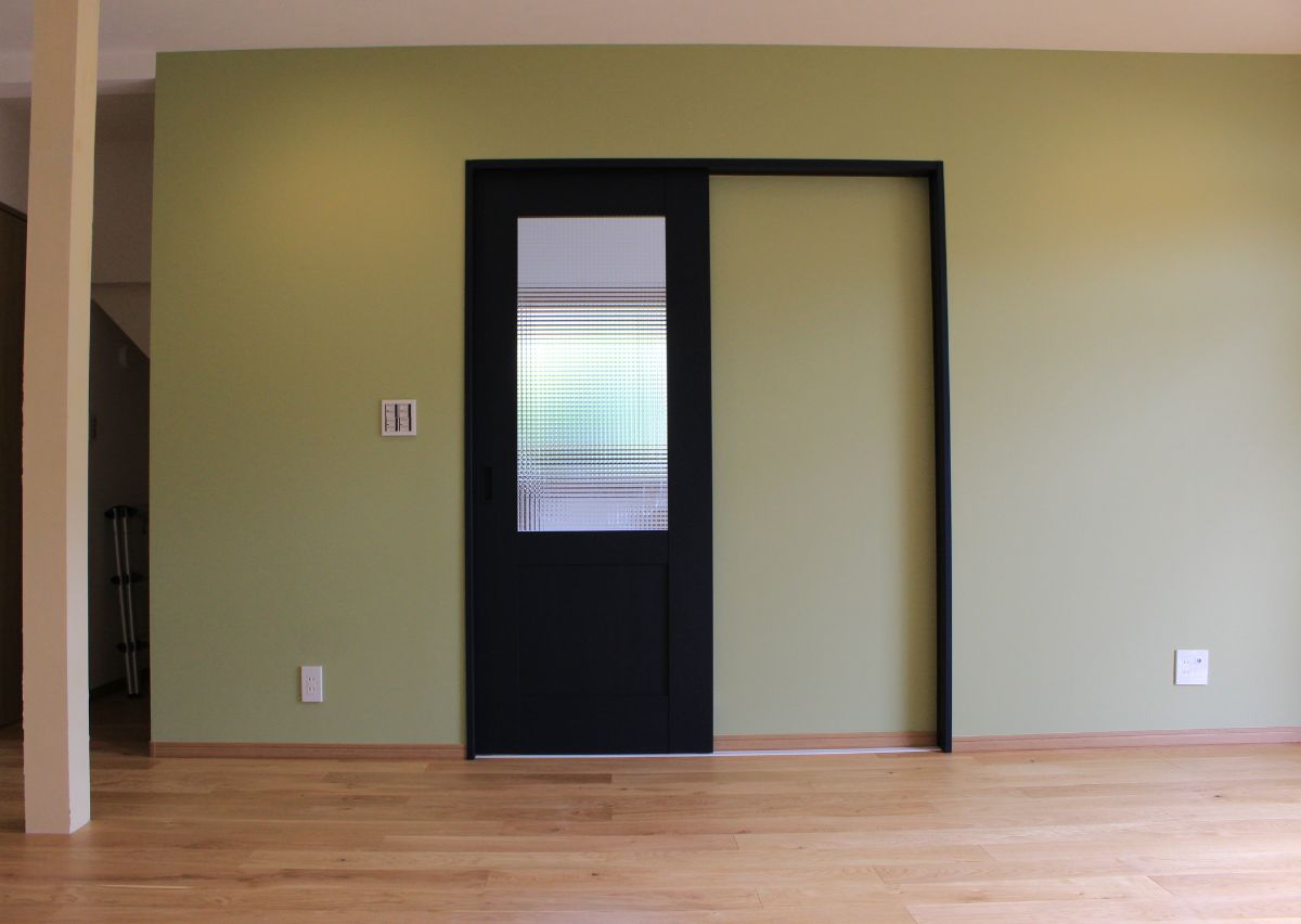 紺色とチェッカーガラスが印象的なリビングドア。グリーンの壁紙と合い、落ち着いたインテリアに。