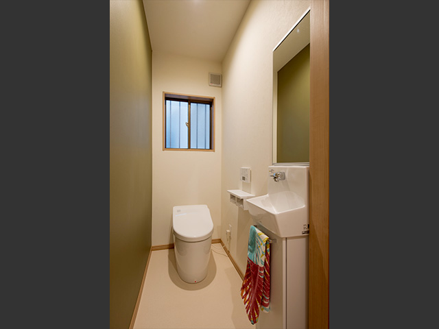 トイレafter：自動開閉もついたタンクレストイレに交換。グリーンのアクセントクロスで落ち着いた空間になりました。