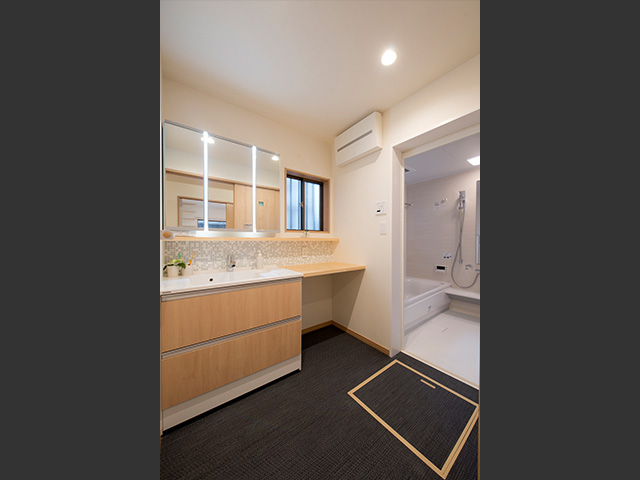 洗面台の横にパイン材のカウンターを延長。下に洗濯物を置いたり、家族が並んで使うこともできます。