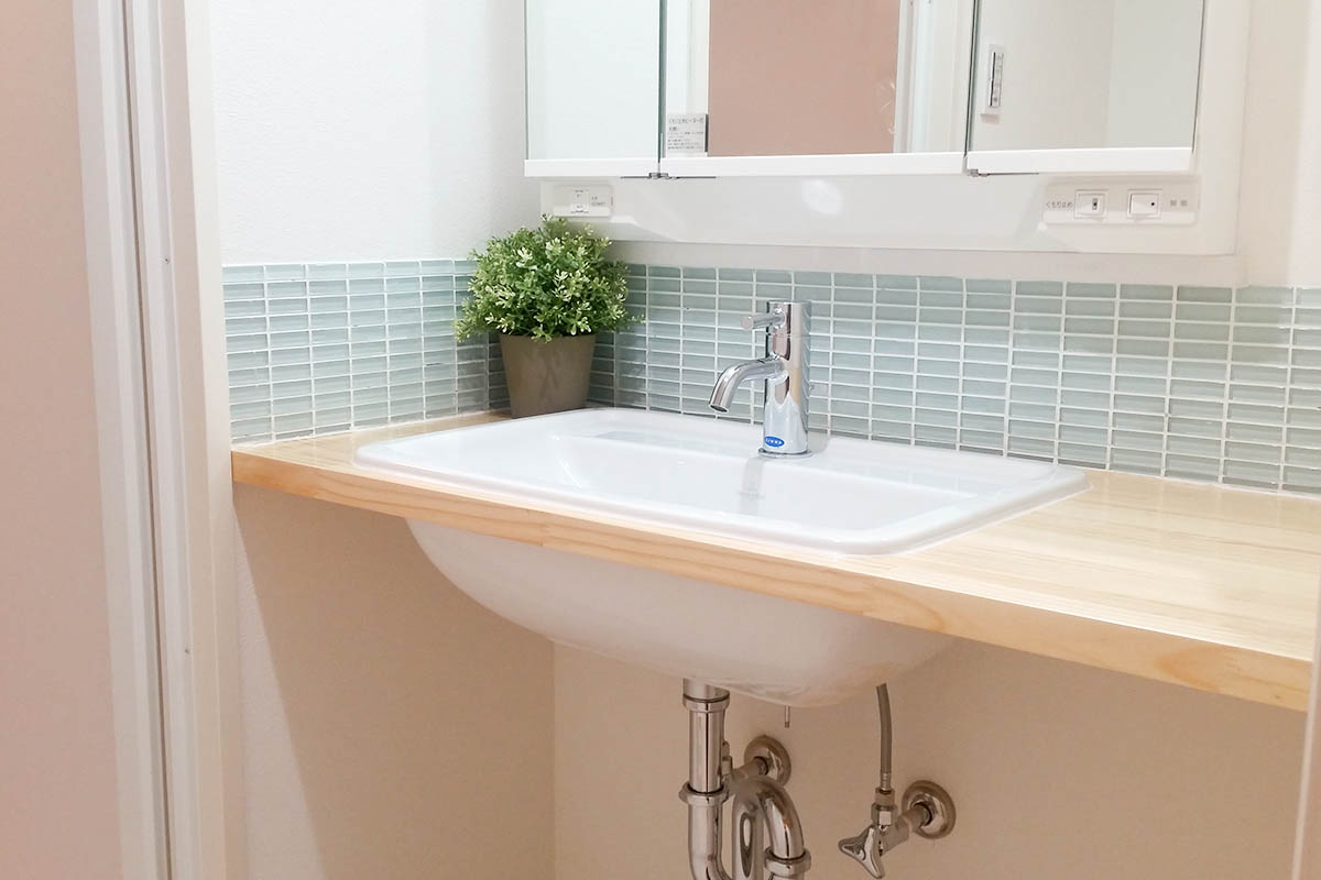洗面after:無垢のパイン材のカウンターとガラスモザイクタイルが印象的な造作洗面台になりました。