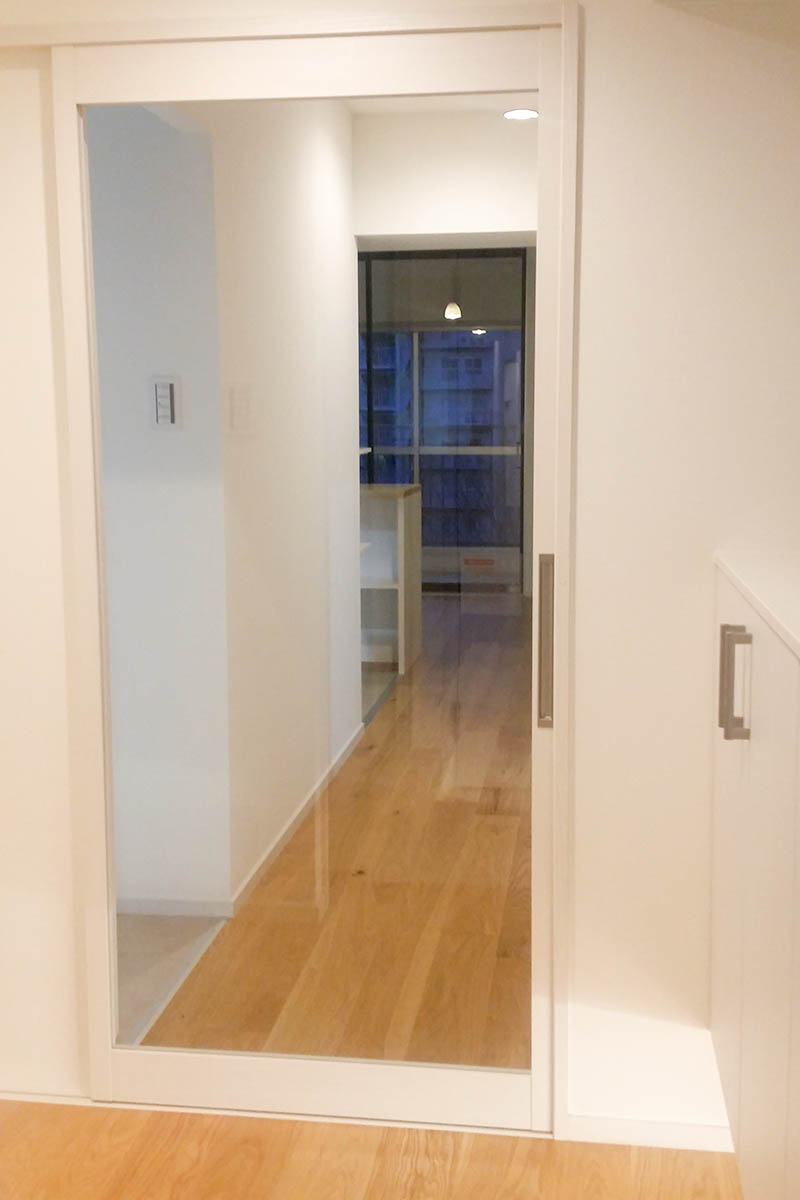 リビングへのドアは大きな透明ガラスのデザイン。玄関にリビングの光も届いて明るくなりました。