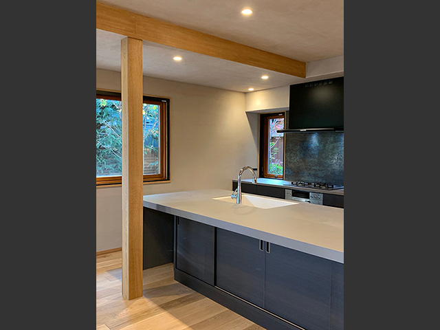 アイランドの下部にも収納たっぷり、ウルトラサーフェイスのカウンター。レンジ前には陶板のような美しい壁