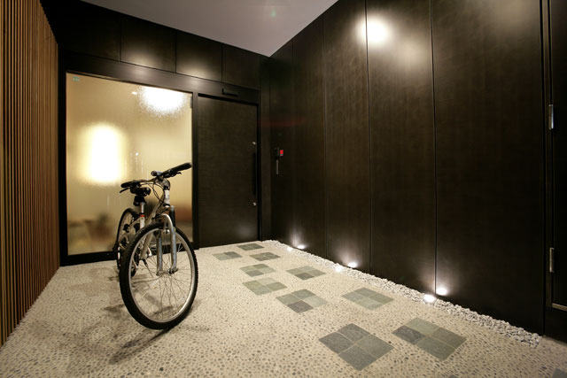 玄関は道路から距離を設け飛石のあるアプローチ空間に。鉄板、木の格子が落ち着きのある和の雰囲気を演出。